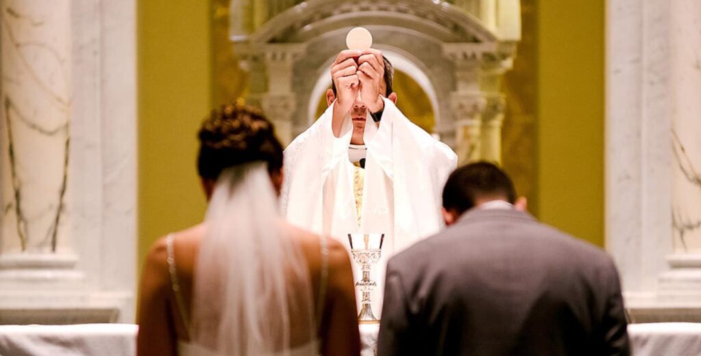 A priest blessing a newlywedded couple. 
