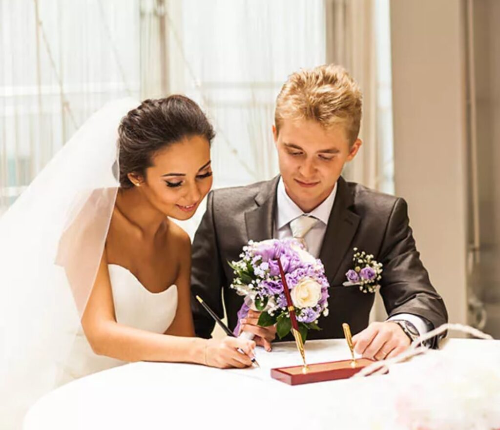 Newlywed couple signing their marriage certificate. 
