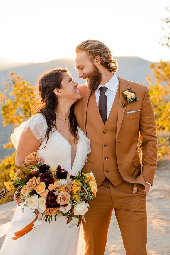 A groom in burnt orange suit with his bride holding a bouquet styled-flower. Image: stockroompicks.com