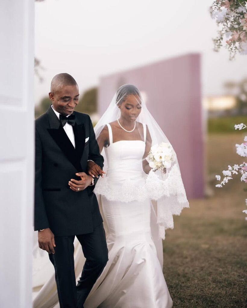 Nigerian bride Motunrayo Fakorede is being walked down the aisle with her father at her wedding to Jomiloju. Image Source: Instagram/@/thedavidmartinss